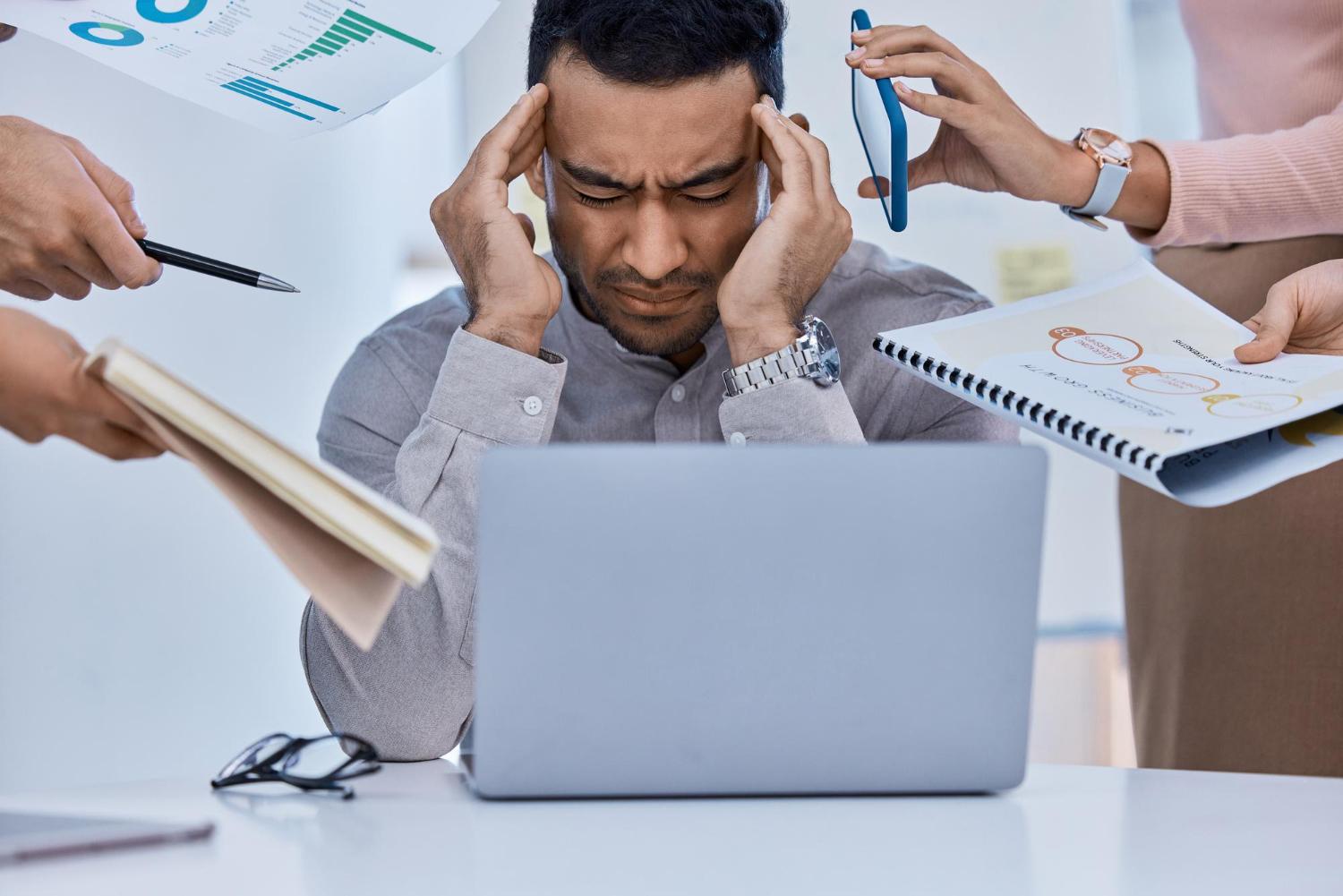 Workplace stress overwhelmed employee at desk with workload pressure